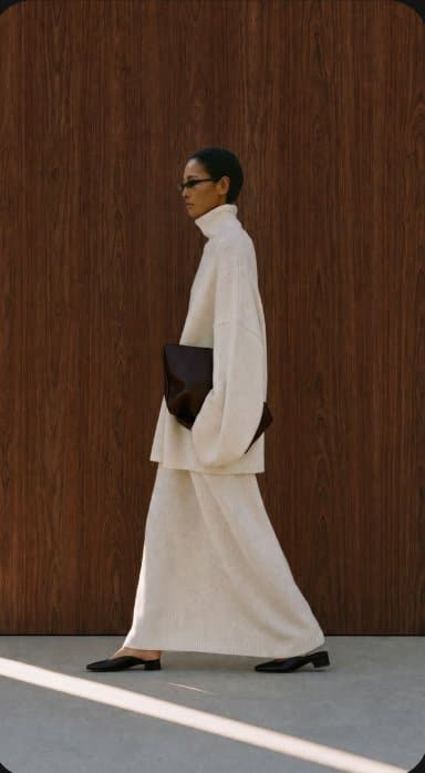 Fashion campaign still, model walking past a wood wall